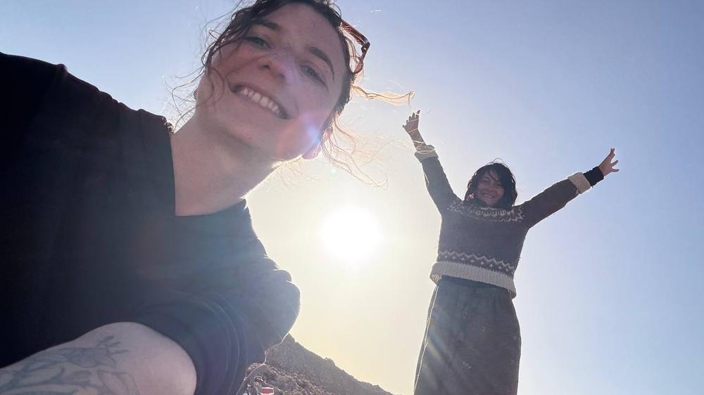 Sumaya and Shahad laughing in the desert sun at Siwa Oasis, one close to the camera and one with both arms raised